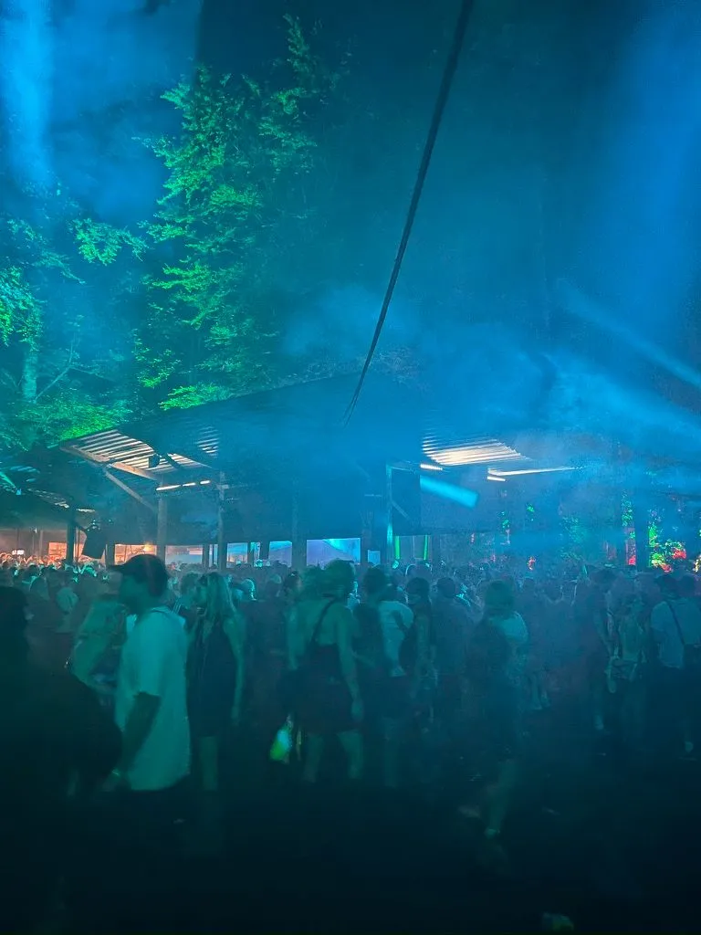 Woodland stage at Houghton Festival in Norfolk with colorful lights filtering through the trees